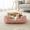 Cat sleeping in the pink plush bed